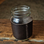 Load image into Gallery viewer, This leather cup sleeve is reusable, sustainable and classy. Stitch with love. Fit Masson jars 16oz.  Ready for a coffee to go?  An all-leather handle for wide mouth 16oz mason jars. Made of 4-5 oz full grain leather in vegtan anniline italian leathe. Riveted with antique brass toned rivets, and no small pieces to wear out and break so this will last a lifetime.
