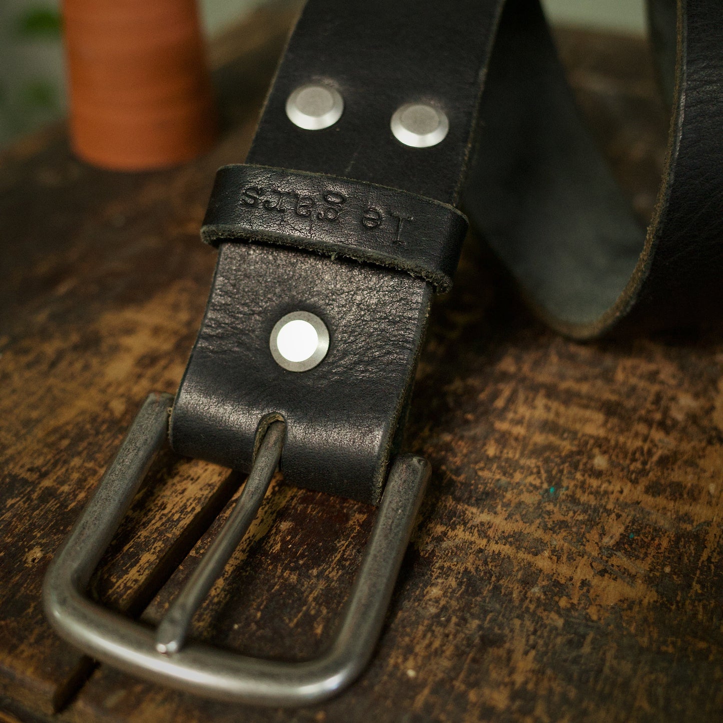 Black leather belt with metal buckle on a wooden surface
