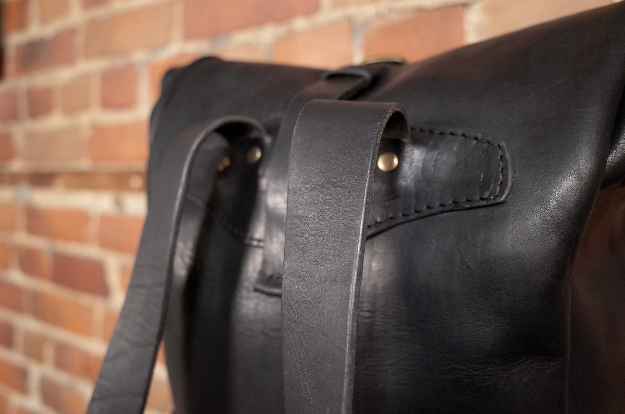 Full-grain black leather roll-top carryall with secure delivery buckle closure
