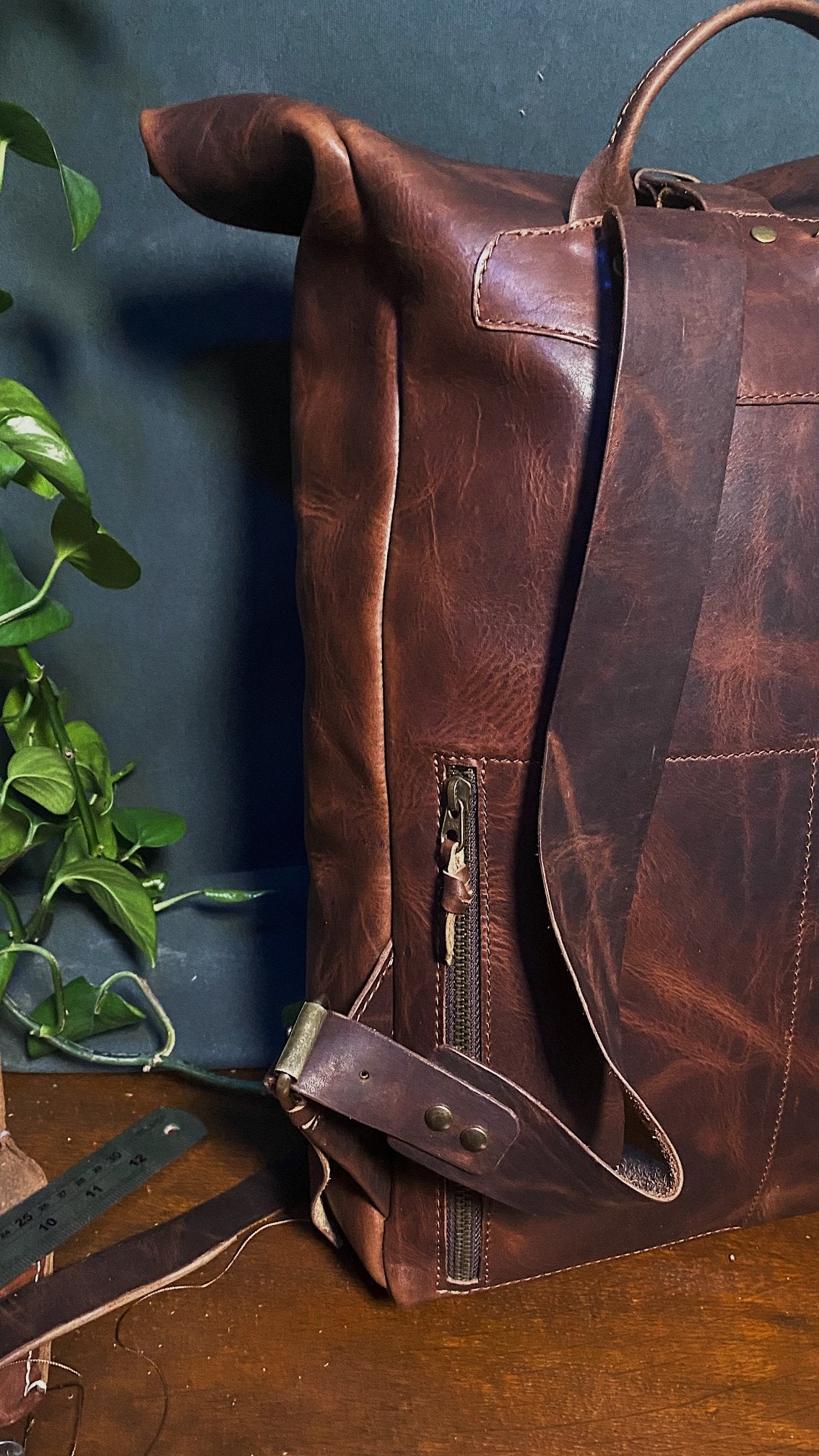 Full-grain chestnut leather roll-top daypack with spacious compartments and G-hook
