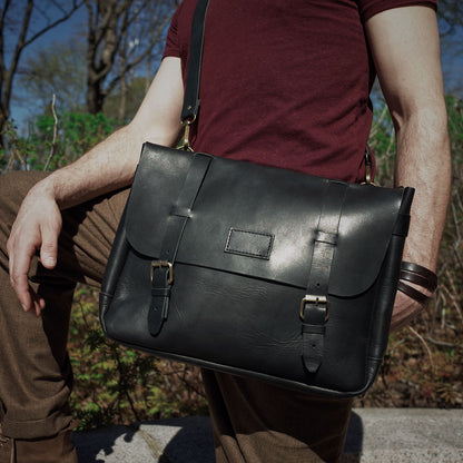 Classic black leather messenger bag for carrying daily essentials
