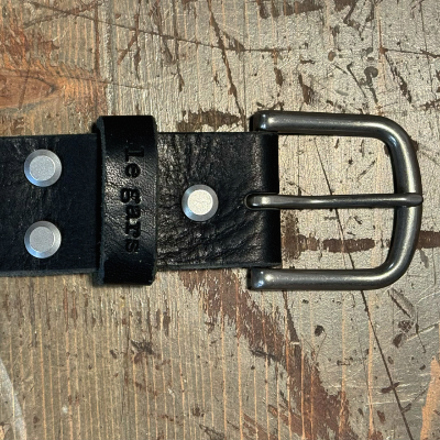 Black leather belt with metal buckle on a textured surface
