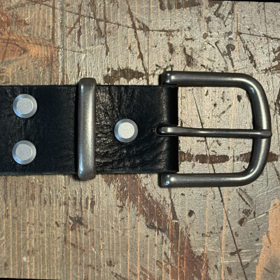 Black leather belt with silver buckle on a textured surface