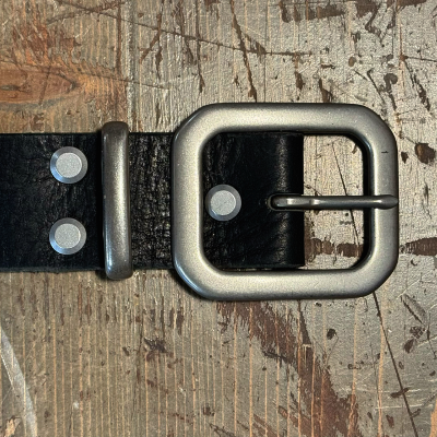 Black leather belt with silver buckle on a textured surface