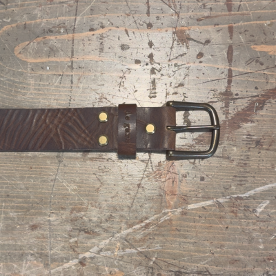 Brown leather belt with a metal buckle on a wooden surface