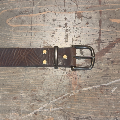 Brown leather belt with a black buckle on a textured surface
