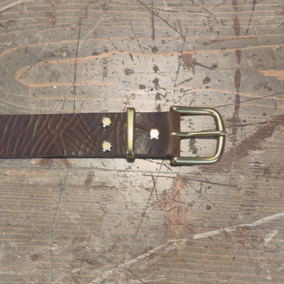 Brown leather belt with a gold buckle on a textured surface
