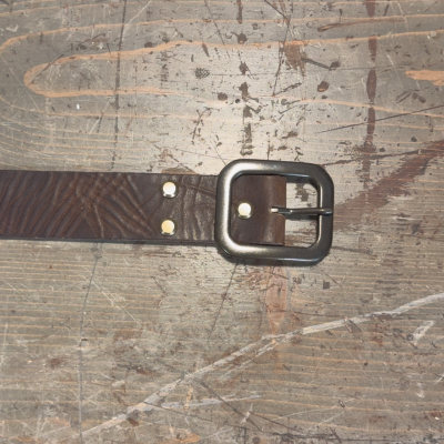Brown leather belt with a buckle on a textured surface