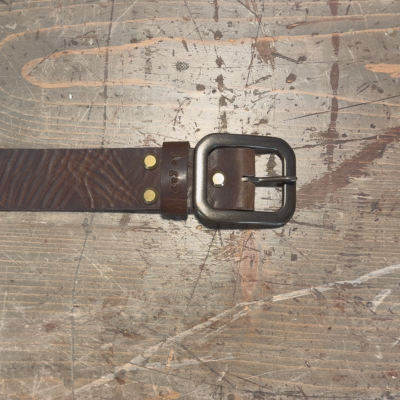 Brown leather belt with a metal buckle on a wooden surface
