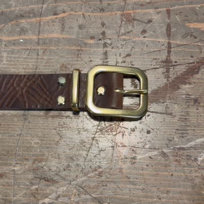 Brown belt with gold buckle on a textured wooden surface