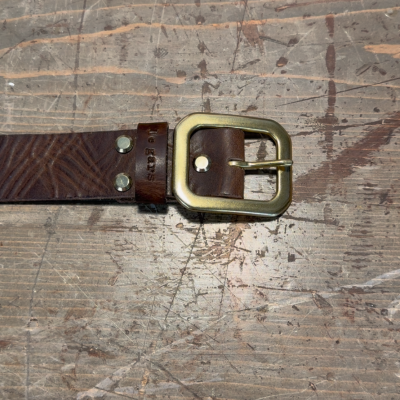 Brown belt with a gold buckle on a textured surface