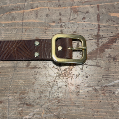 Brown belt with a gold buckle on a textured surface