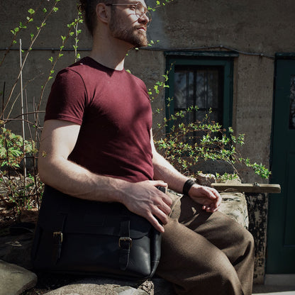 Hand-stitched black leather bag with multiple compartments
