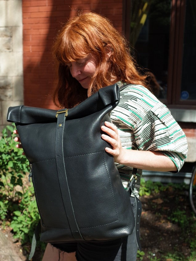 Spacious black leather roll-top knapsack with premium brass hardware
