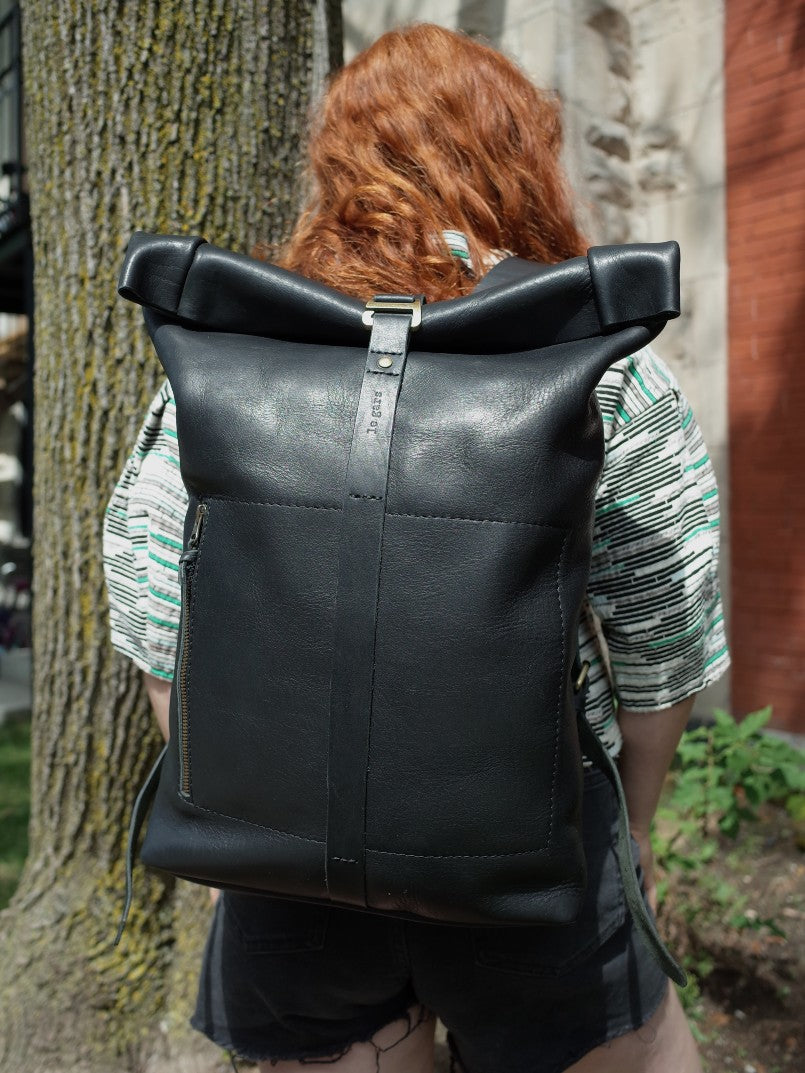 Handcrafted black leather roll-top daypack with secure G-hook fastening
