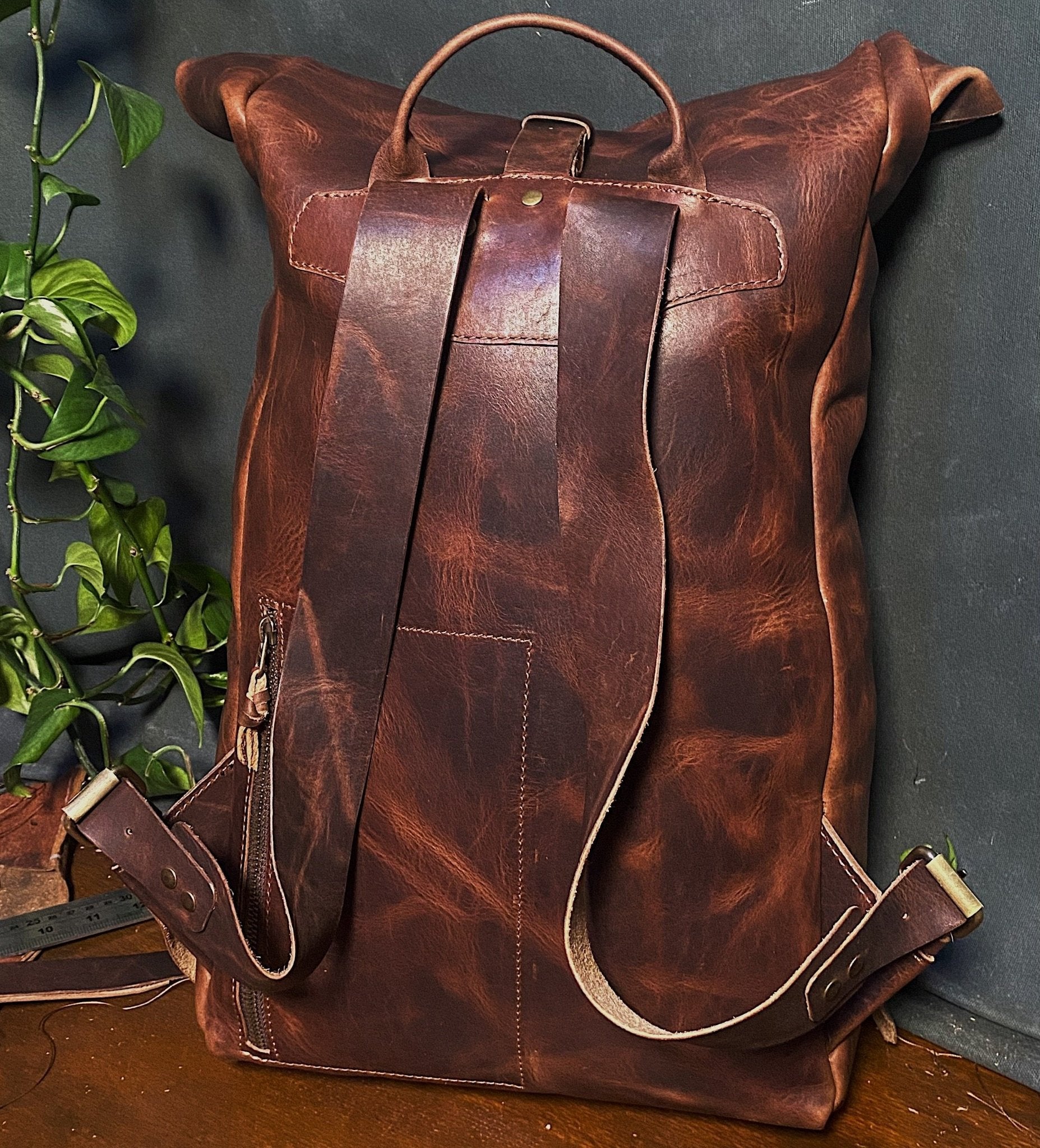 Premium dark-brown leather roll-top pack with adjustable straps and delivery buckle

