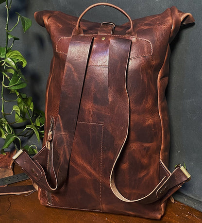 Premium dark-brown leather roll-top pack with adjustable straps and delivery buckle

